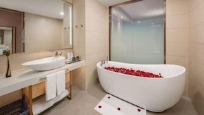 A modern bathroom with a freestanding bathtub filled with rose petals, a large mirror, and a white sink. - Lavande Hotel(Guangzhou Baiyun Airport Shuguang Road) (Guangzhou)