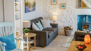 A cozy living room with a sofa, a small table with a lamp, a bookshelf, and a fireplace. - Picked for its wonderful character and charm and stunning sea views to enjoy. (Goodwick)