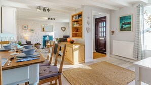 A dining area with a wooden table set for four, a fireplace, and a bookshelf. - Picked for its wonderful character and charm and stunning sea views to enjoy. (Goodwick)