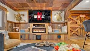 Un salon chaleureux avec une cheminée, un téléviseur avec Netflix et une décoration rustique.