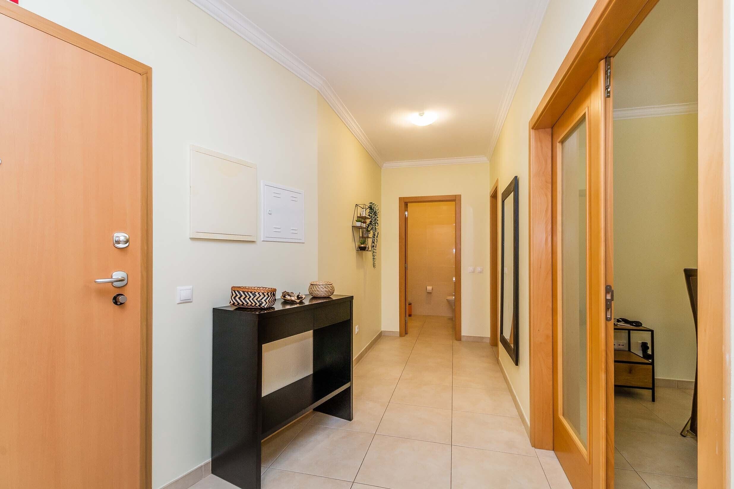 A hallway with a wooden door, a black console table, and a wooden door frame.