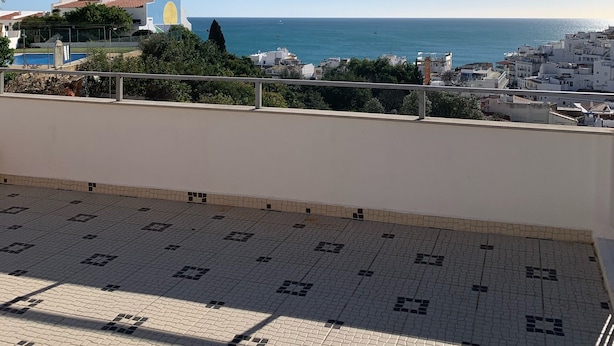 Un balcon carrelé avec vue sur la mer et les bâtiments.