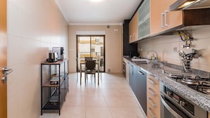 Une cuisine moderne équipée d’une cuisinière à gaz, de placards et d’un coin repas avec des chaises.