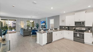 A modern kitchen with white cabinets, a built-in microwave, and a stainless steel oven.
