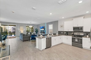 A modern kitchen with white cabinets, a built-in microwave, and a stainless steel oven.