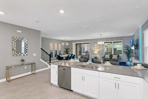 A modern kitchen with a central island, white cabinetry, and a dining area with blue chairs.