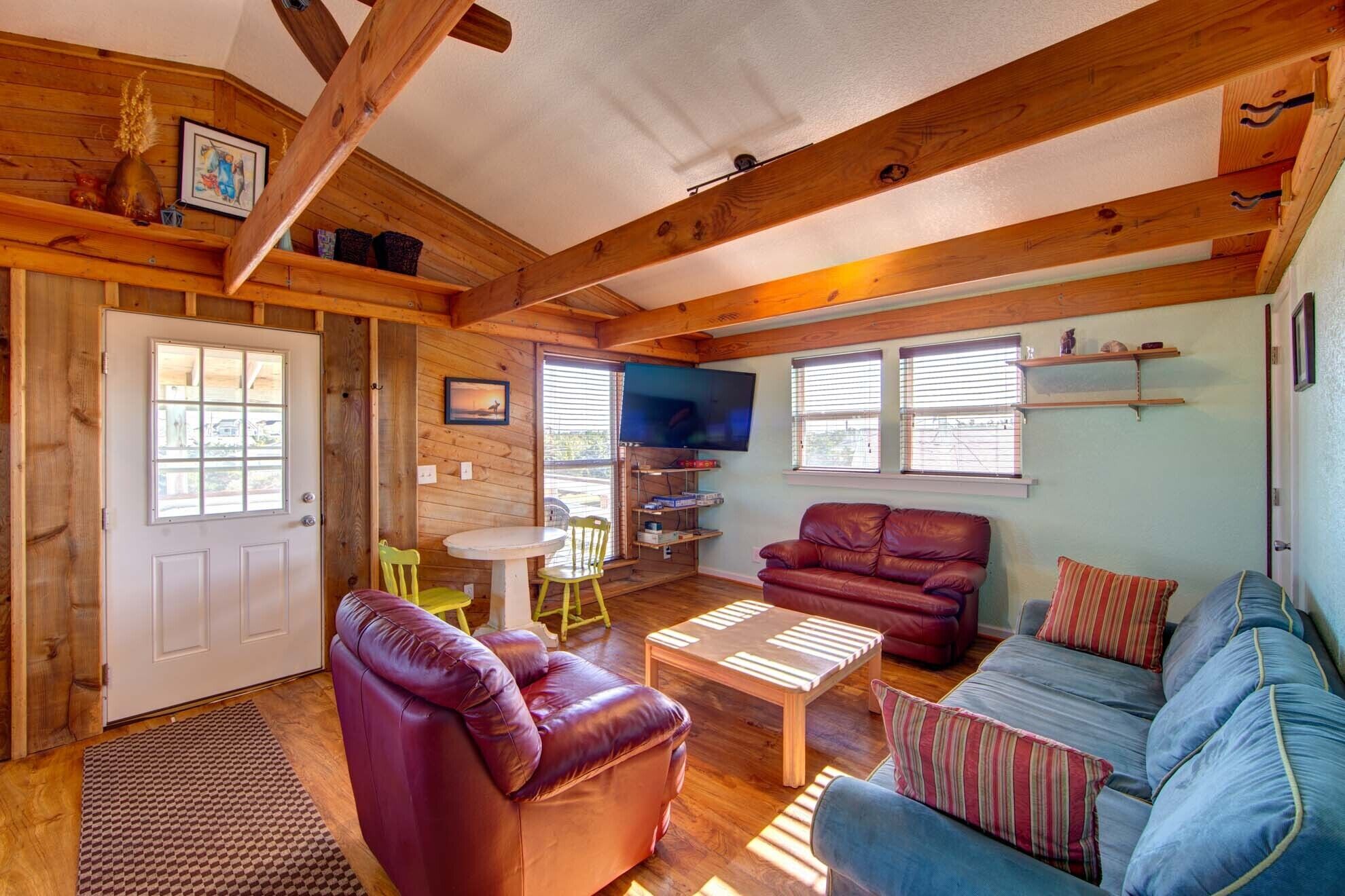 A cozy living room with wooden beams, a television, a fireplace, and a dining area with a table and chairs.