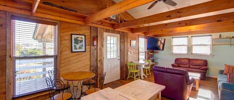 A cozy cabin interior with a dining area, a sofa, and a TV.
