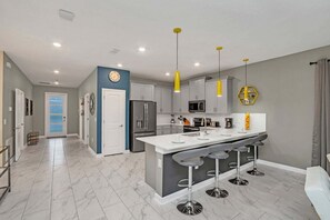 A modern kitchen with a central island, grey cabinets, and a yellow pendant light.