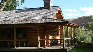 A log cabin with a porch, a chimney, and a bicycle.