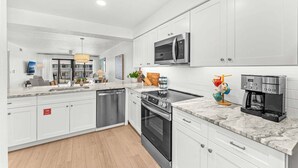 Una cocina moderna con armarios blancos, electrodomésticos de acero inoxidable y encimera de mármol.
