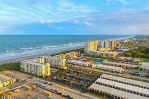 A coastal cityscape with high-rise buildings, a beach, and a parking lot.