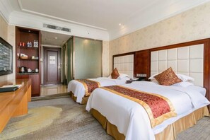 Habitación de hotel con dos camas, un escritorio y un televisor.