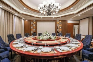 Una mesa redonda con sillas, una araña y un centro de mesa floral.