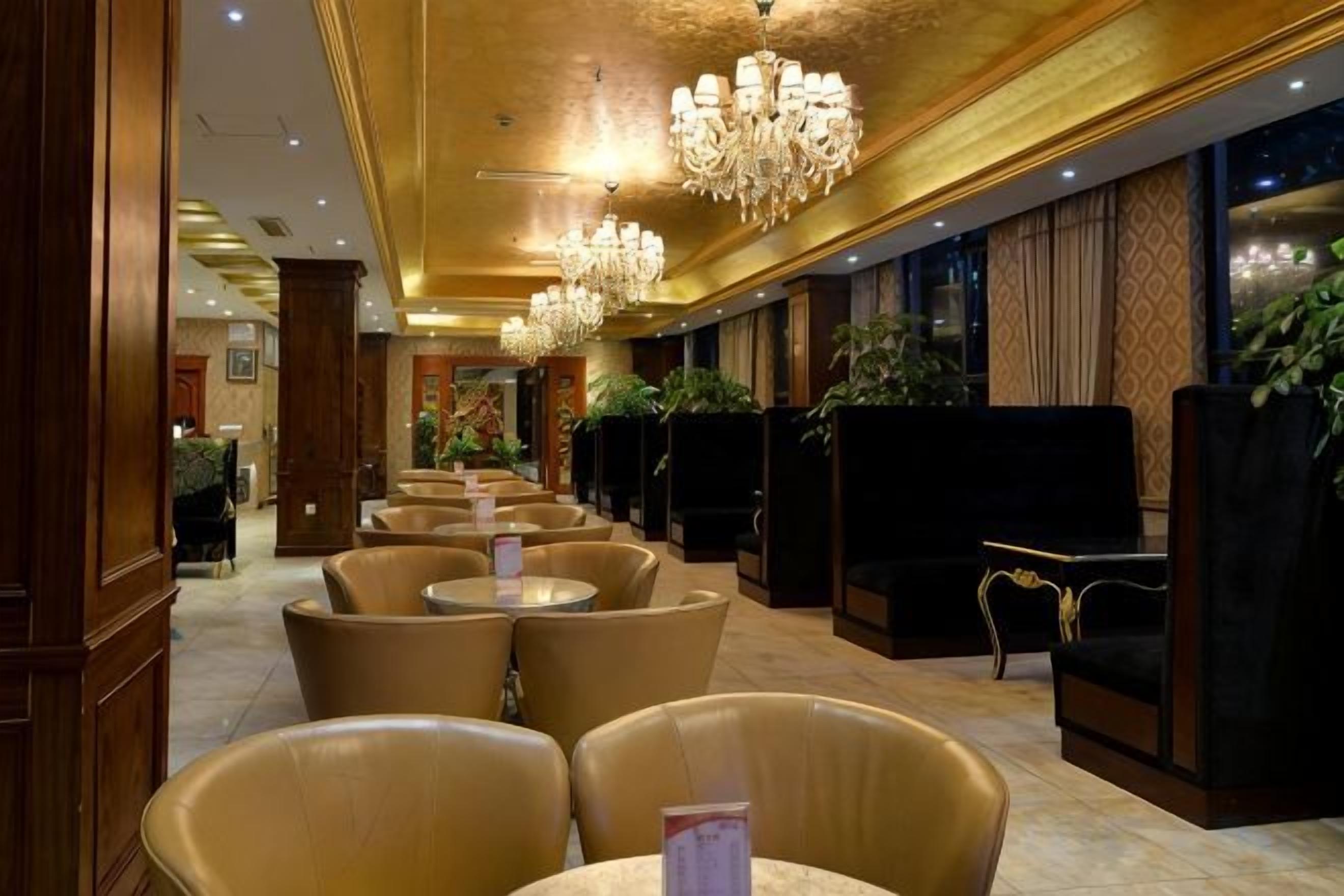 A hotel lobby with seating areas, chandeliers, and a reception desk.