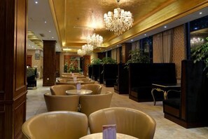 A hotel lobby with seating areas, chandeliers, and a reception desk. - Garden Hotel (Yilong)