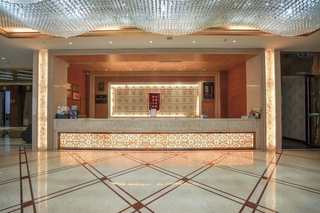 A reception area with a tiled floor, a reception desk, and a decorative ceiling.