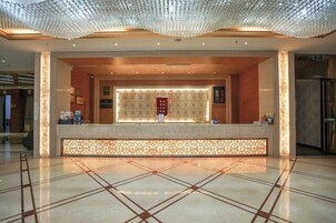 Zona de recepción con suelo de baldosas, mostrador y techo decorativo.