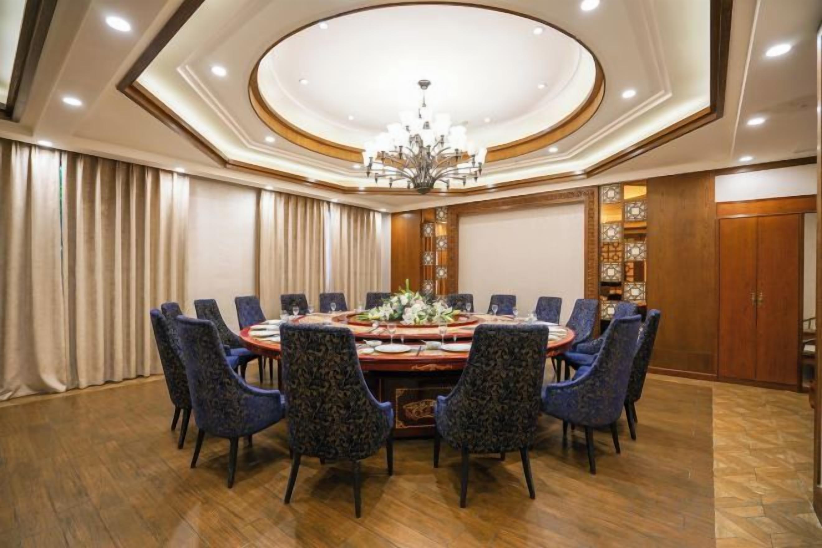 A conference room with a round table, chairs, and a chandelier.