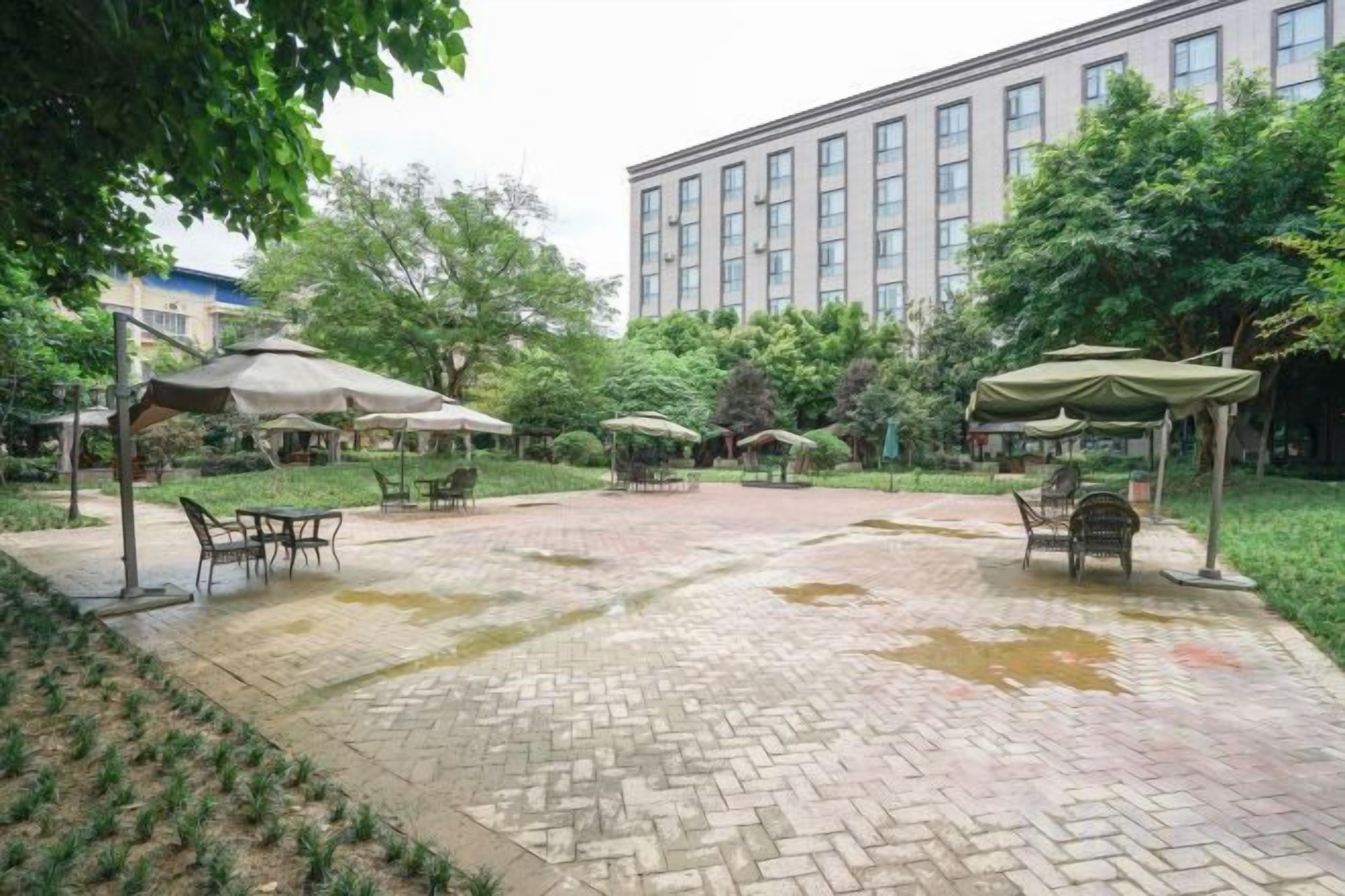 An outdoor patio area with brick flooring, tables, chairs, and umbrellas.
