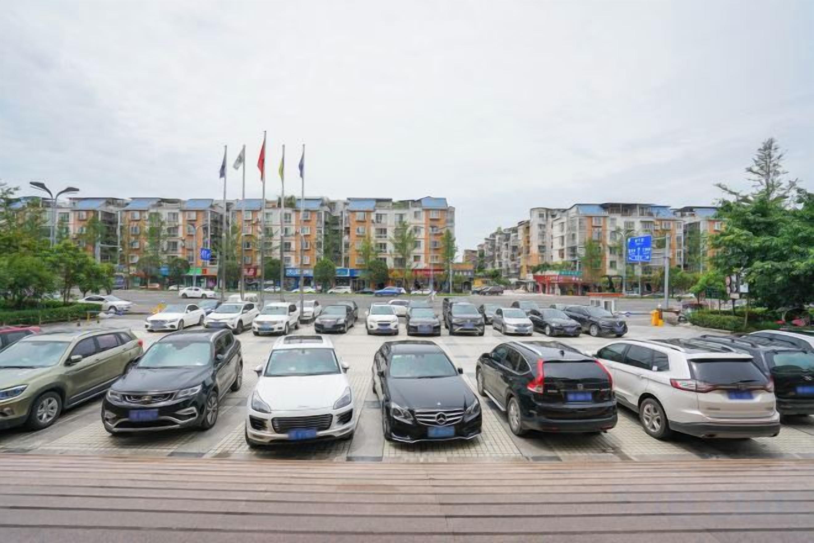 A parking lot with multiple cars and a row of buildings in the background.