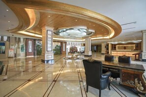 A spacious lobby with a central fountain, a reception desk, and a modern ceiling design. - Garden Hotel (Yilong)