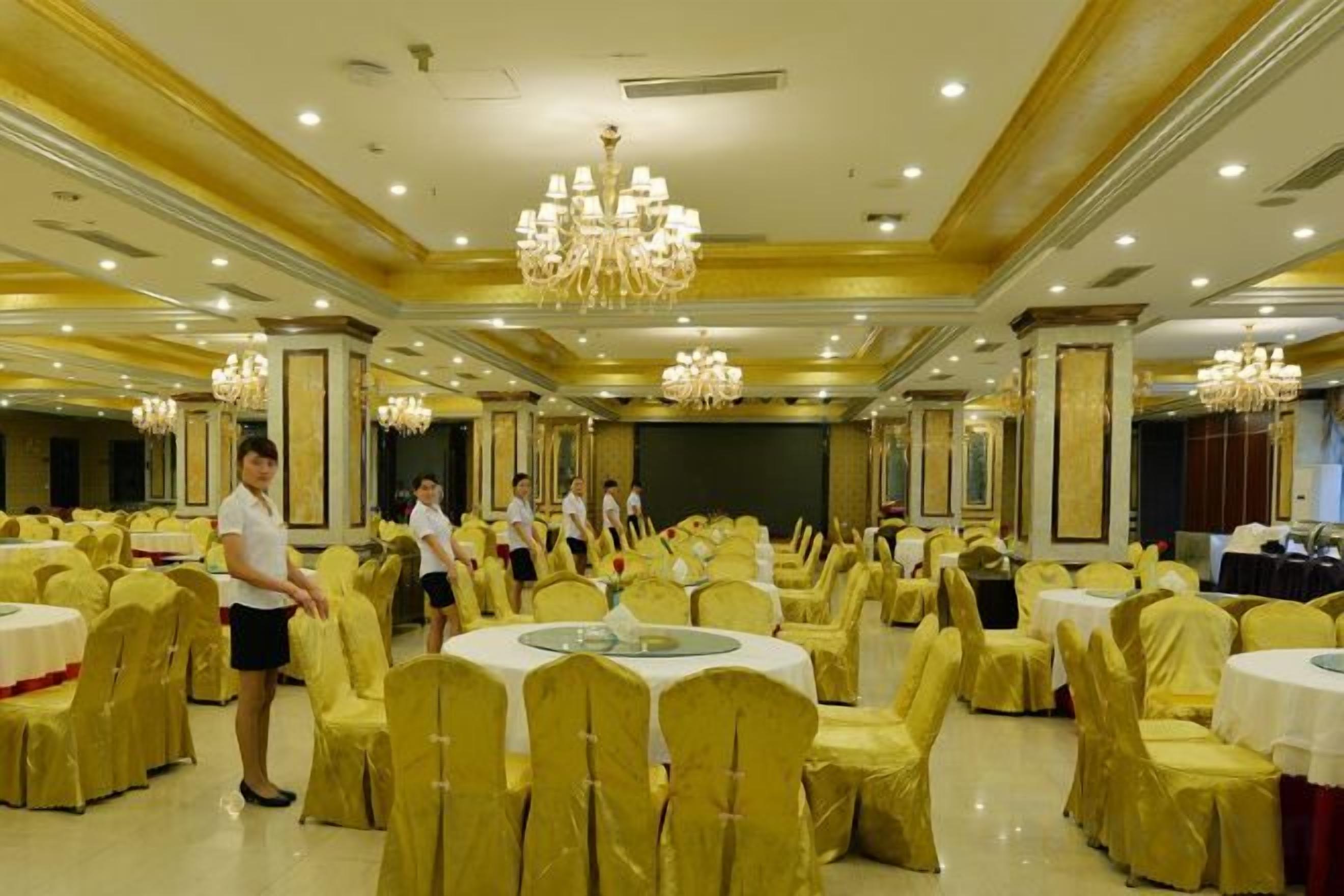A banquet hall with round tables, chairs, and a stage.