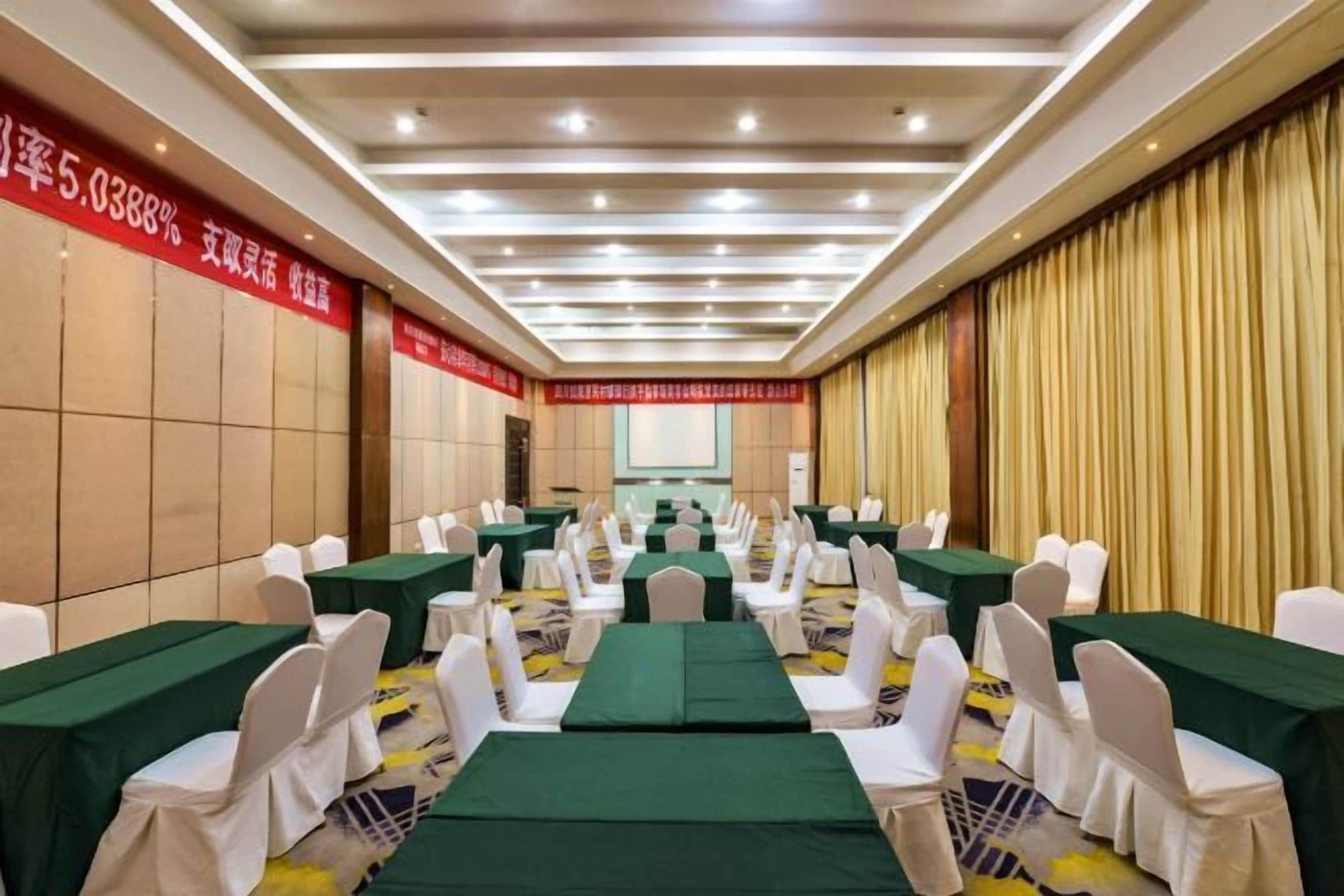 A conference room with tables and chairs, a podium, and a large screen.
