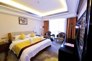 A hotel room with a large bed, a desk, a chair, and a television.