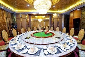 A conference room with a round table, chairs, and a chandelier. - Garden Hotel (Yilong)