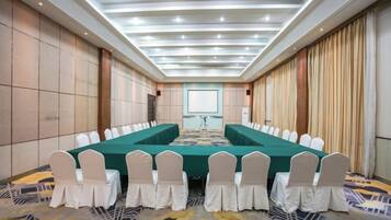 A conference room with a long table, white chairs, and a projector screen.