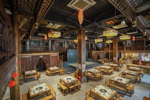 A traditional Chinese restaurant interior with wooden furniture, lanterns, and a central pillar. - Garden Hotel (Yilong)
