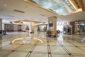 A spacious lobby with a polished floor, a central seating area, and a large chandelier. - Garden Hotel (Yilong)