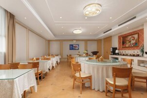 Un comedor de hotel con mesas redondas, sillas y una zona de bar.