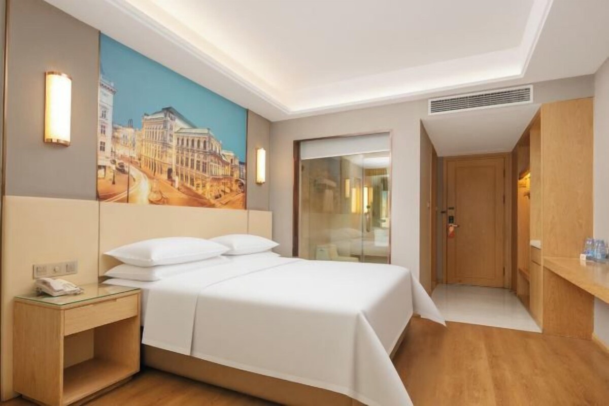 Ein Hotelzimmer mit einem Bett, einem Nachttisch und einem Bild an der Wand.
