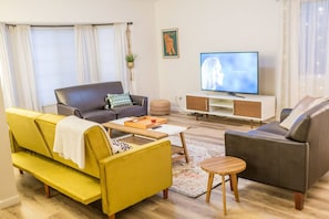 A living room with a sofa, armchair, coffee table, and TV.