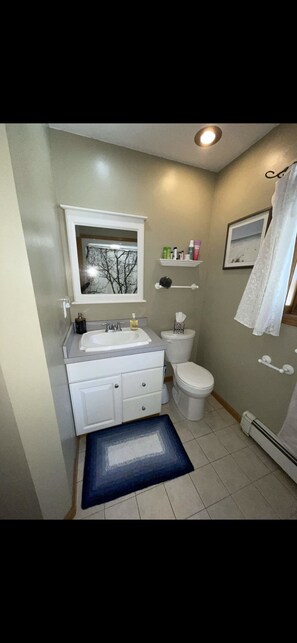 A bathroom with a white sink, toilet, and vanity. There is a window above the sink, a towel rack, and a picture on the wall. - 3bd, 3bath (Gaylord)
