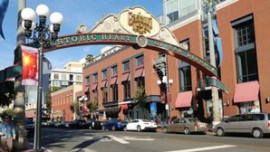 Een straatnaambord met de tekst 'Historic Heart of San Diego' en een gebouw met grote ramen en een rode luifel.