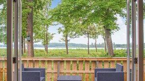 A deck with wicker furniture overlooking a lake, surrounded by trees.