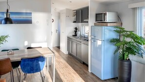 A modern kitchen with a blue refrigerator, stainless steel cabinets, and a microwave on top.
