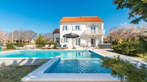 A two-story house with a swimming pool, outdoor seating, and a garden. - Beautiful home in Tinj (Tinj)