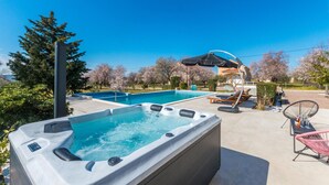 A hot tub and a pool with lounge chairs and umbrellas. - Beautiful home in Tinj (Tinj)