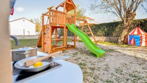 A wooden play structure with a slide and climbing elements, a tent, and a table with kitchen utensils. - Beautiful home in Tinj (Tinj)
