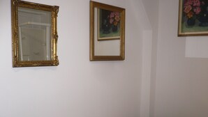 Une chambre à coucher avec un lit, un miroir et deux tableaux encadrés accrochés au mur.