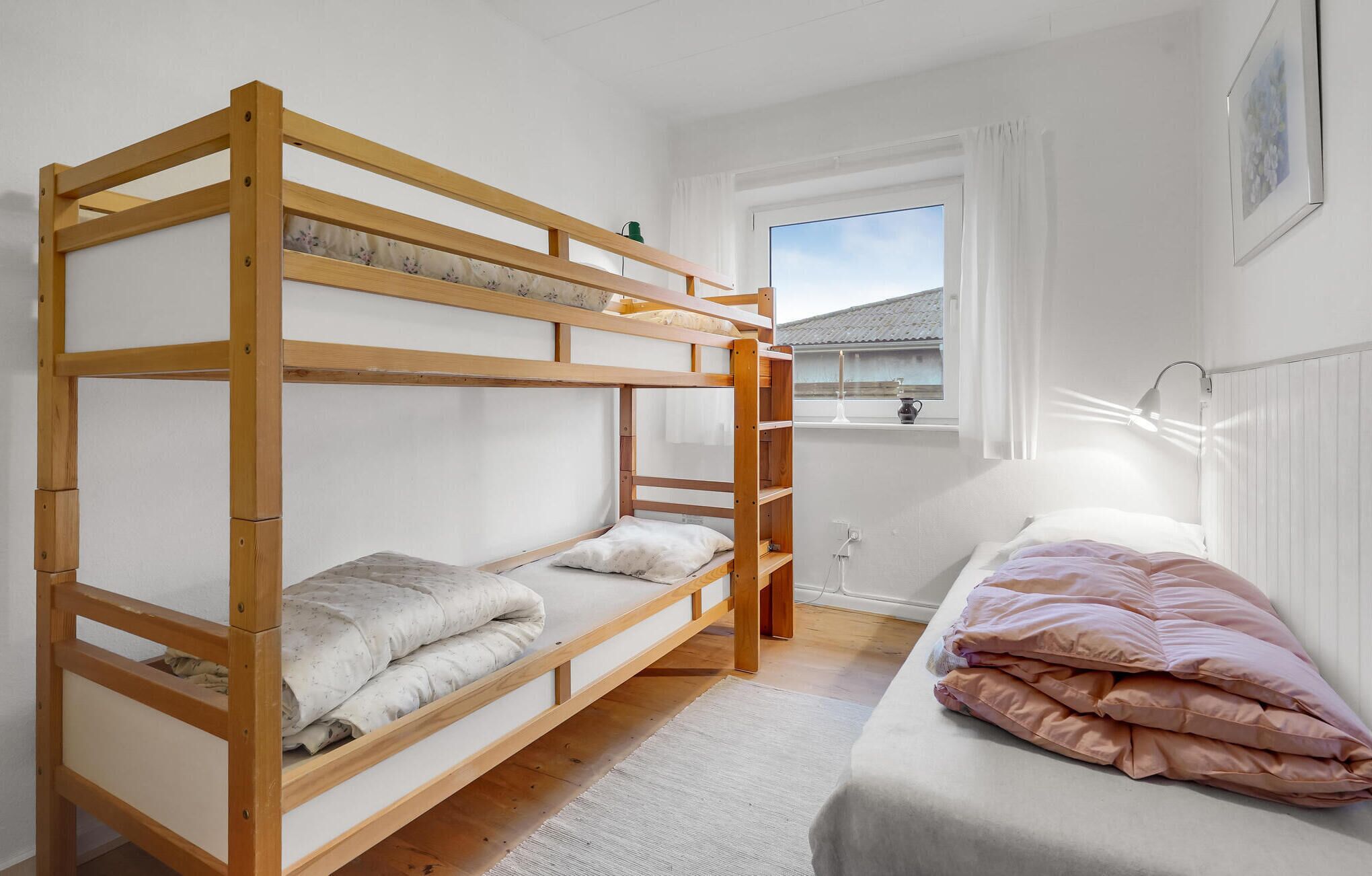 Une chambre avec un lit superposé, une fenêtre et un lit simple.
