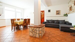 A living room with a stone coffee table, a dark sofa, and a dining area with wooden chairs and a table.