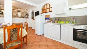 A compact kitchen with white cabinets, a built-in oven, and a dining area with a wooden table and chairs.