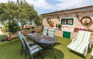 An outdoor patio with a round table and chairs, a stone wall, and a view of the sea. - Gorgeous apartment in Blace with house sea view (Blace)