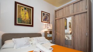 Een hotelkamer met een bed, een nachtkastje, een lamp en twee ingelijste schilderijen aan de muur.
