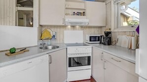 A compact kitchen with white cabinets, a Bosch dishwasher, a microwave, a coffee maker, and a window providing natural light. - Stunning home in Sydals with sauna (Sydals)
